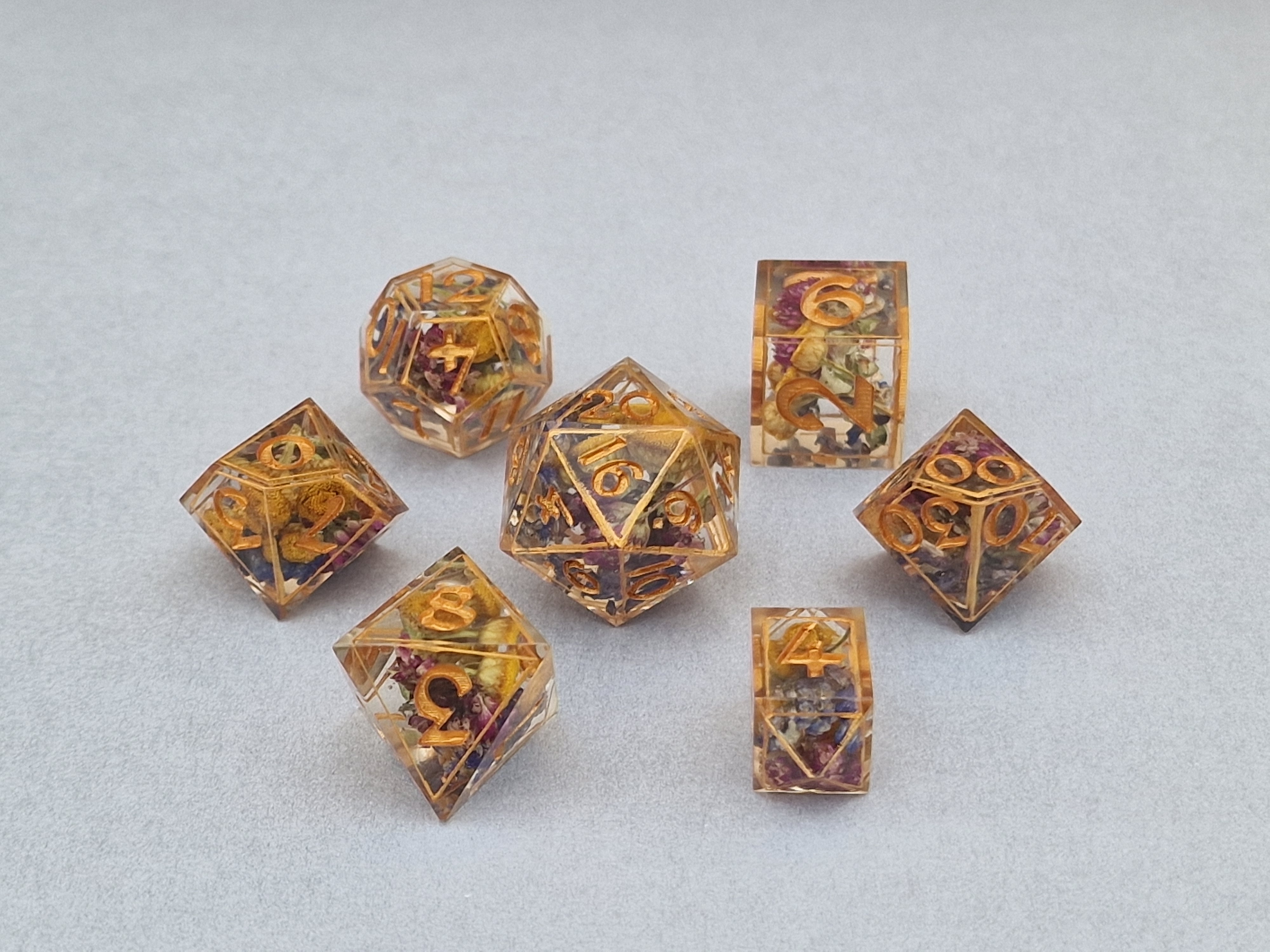 Tiny colourful flowers rest in clear resin, outlined with golden edges and matching numbers.