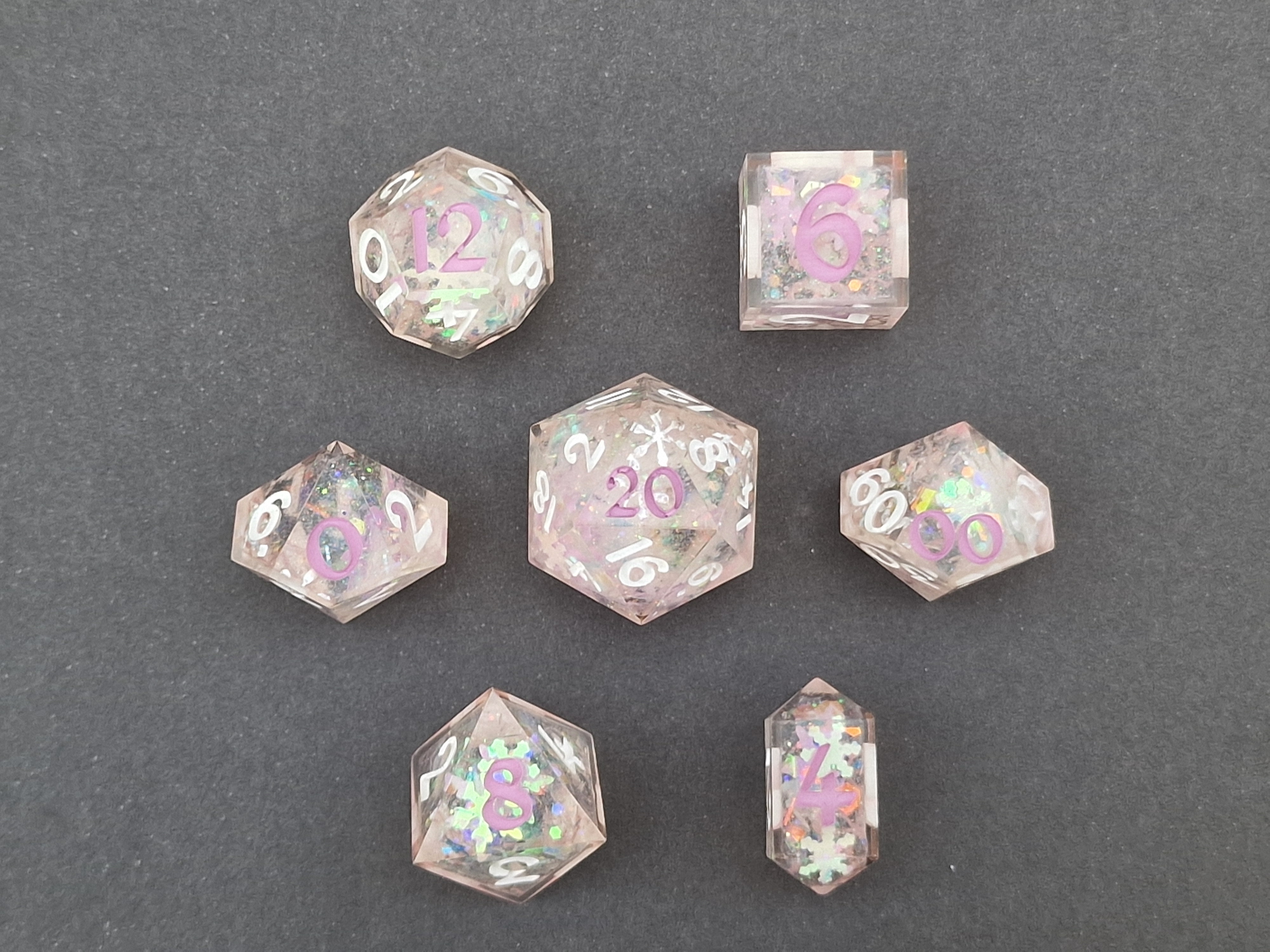 Pale pink dice hold iridescent snowflakes and shimmer, finished with white and lilac numbers.